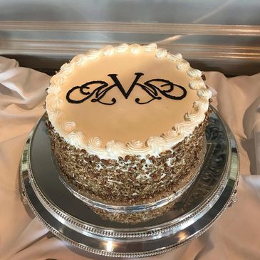 Elegant round cake with white frosting and decorative initials.