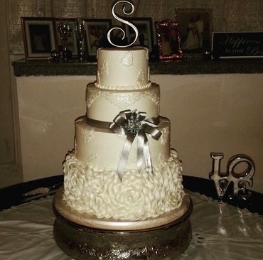 Elegant three-tier white wedding cake with floral decorations and a silver bow.