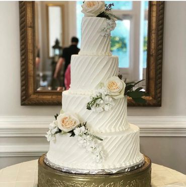 Elegant white tiered wedding cake with floral decorations.