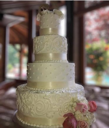 Elegant four-tier white wedding cake with intricate designs and flowers.