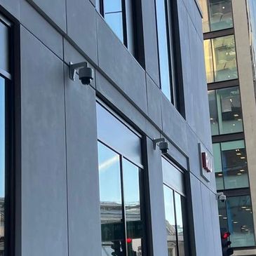 Urban street with modern buildings and pedestrians crossing at traffic lights.