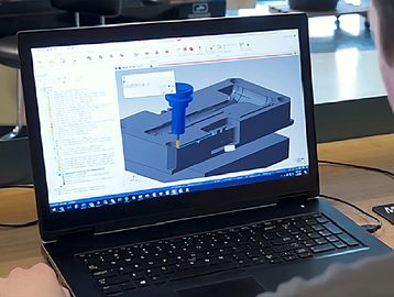 Person working on 3D CAD modeling software on a laptop.