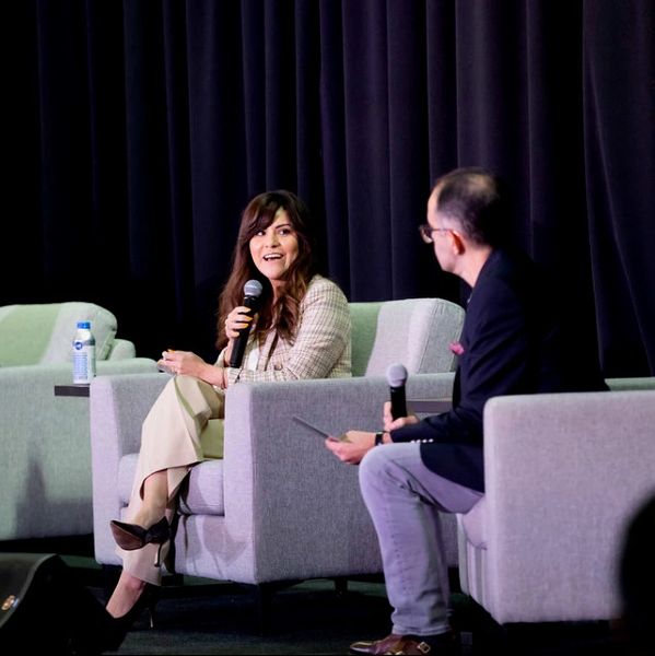 Fatima speaking to host on stage.