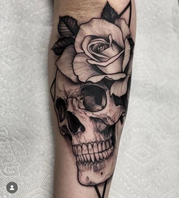 Black and grey tattoo of a skull with a large rose on top.