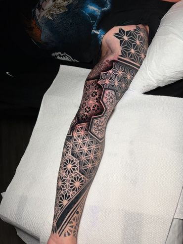 Geometric blackwork tattoo sleeve featuring intricate repeating patterns, precise linework, and detailed dotwork shading.