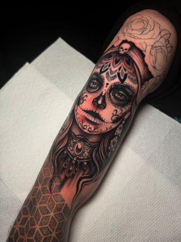 Black and grey Día de los Muertos-inspired woman portrait tattoo featuring sugar skull makeup, ornamental patterns, and detailed shading.