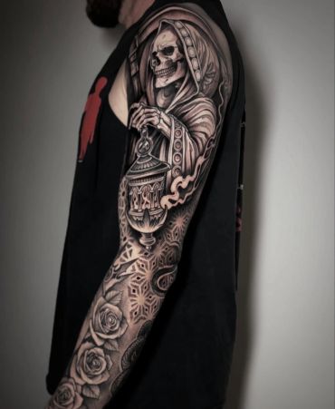 Black and grey tattoo sleeve featuring dark illustrative imagery, intricate geometric patterns, ornamental details, and detailed shading.