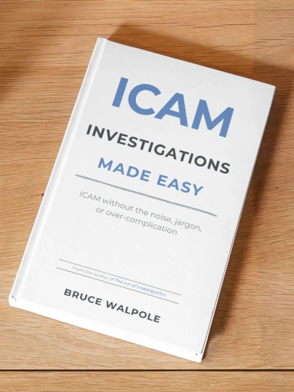 Book titled 'ICAM Investigations Made Easy' by Bruce Walpole on a wooden table.