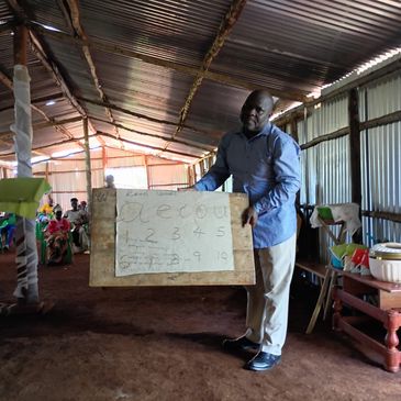 Man holding a whiteboard with numbers in a classroom.