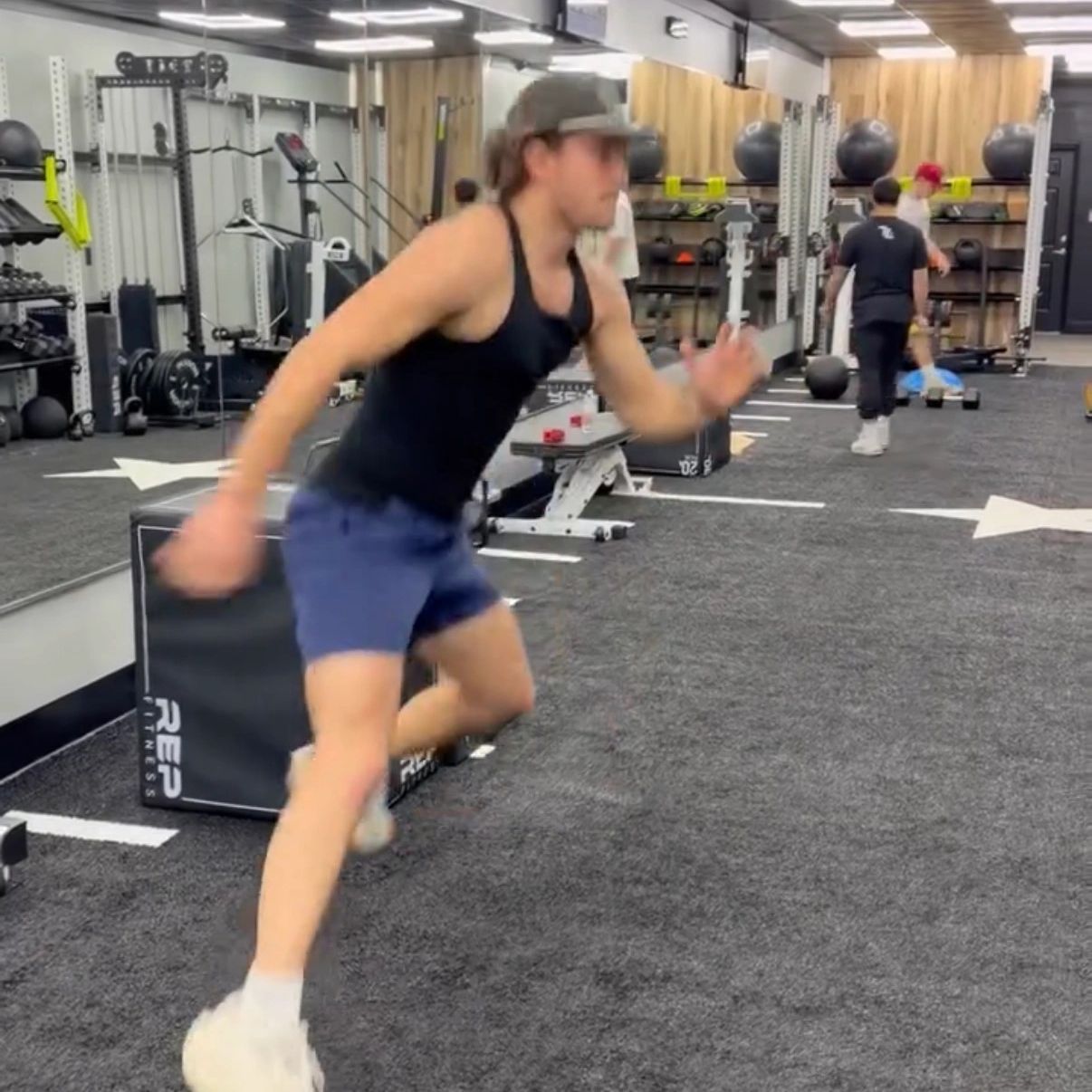 Man sprinting indoors in a gym setting.