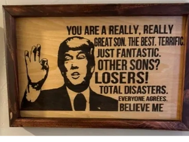 Wooden plaque with a caricature and humorous message praising a son.