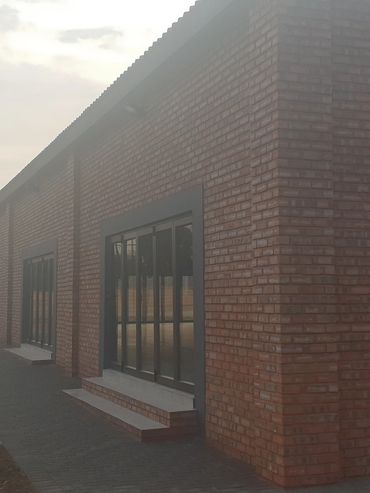 A brick building with large windows beside a fenced outdoor area during dusk.