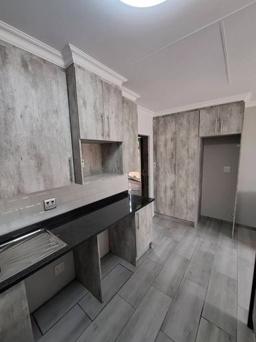 Modern kitchen with grey wood cabinets and black countertop.
