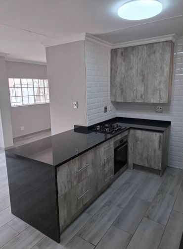Modern kitchen with black countertops and wood-finished cabinets.