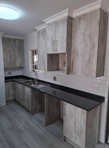 Modern kitchen with gray wood cabinets and black countertop.
