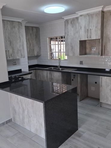 Modern kitchen with grey cabinets and black countertops.