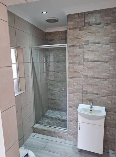 Modern bathroom with a glass-enclosed shower and a white sink cabinet.