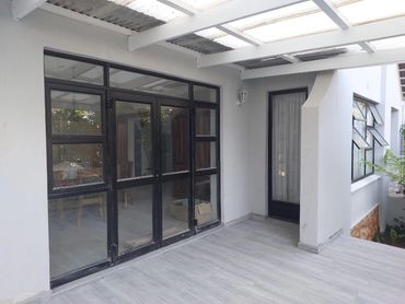Modern patio with glass doors and tiled flooring under a translucent roof.