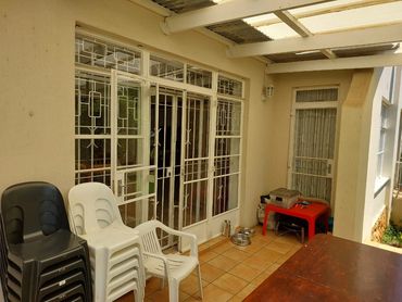 Outdoor patio with stacked chairs and a small red table.