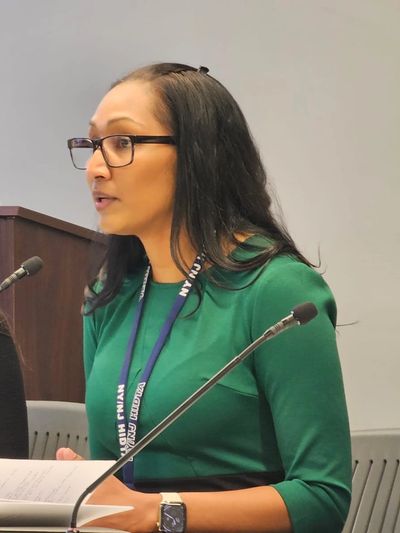 Two women engaged in a discussion at a conference table with microphones.