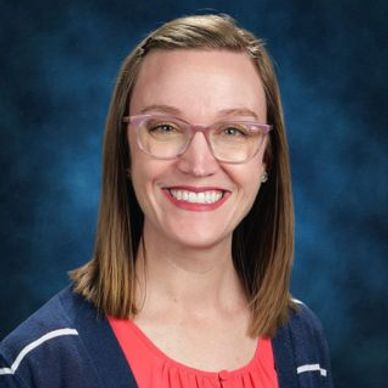 Smiling woman with glasses and shoulder-length hair in a professional portrait.