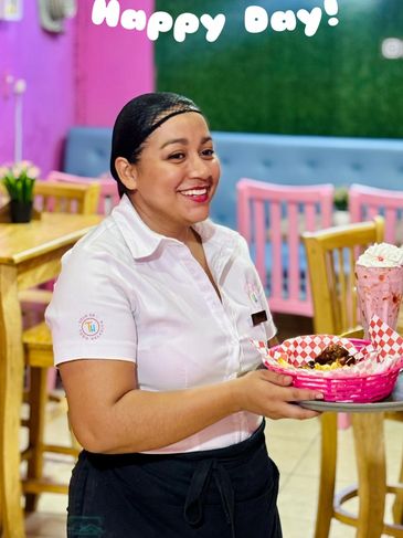 Smiling waitress serving food in a colorful restaurant.