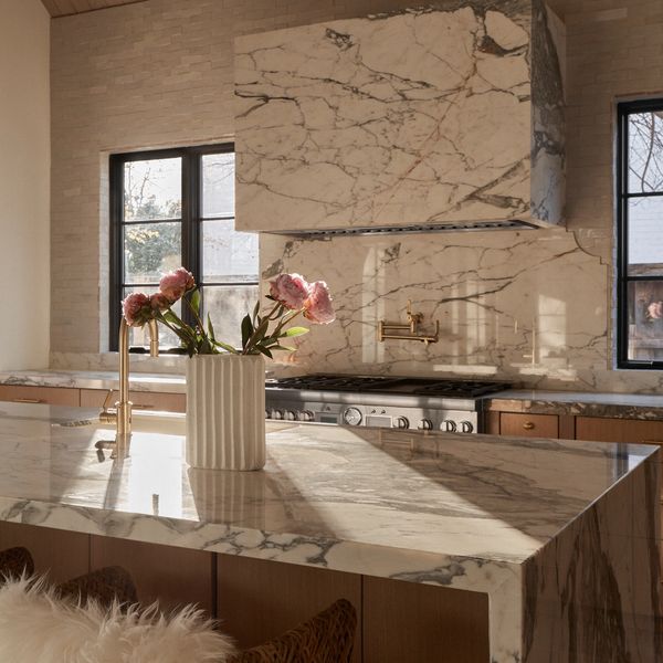 Elegant kitchen with marble countertops and soft pink flowers in a white vase.