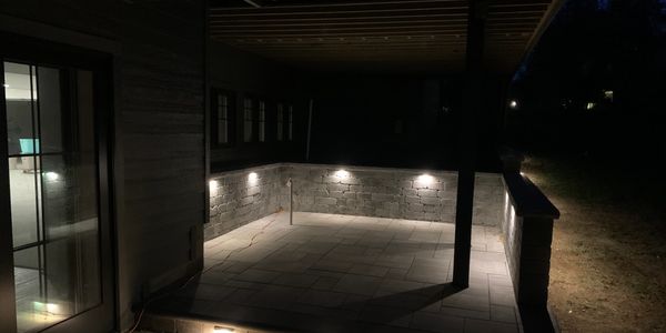Outdoor living space illuminated with custom lighting by Simmons Landscaping