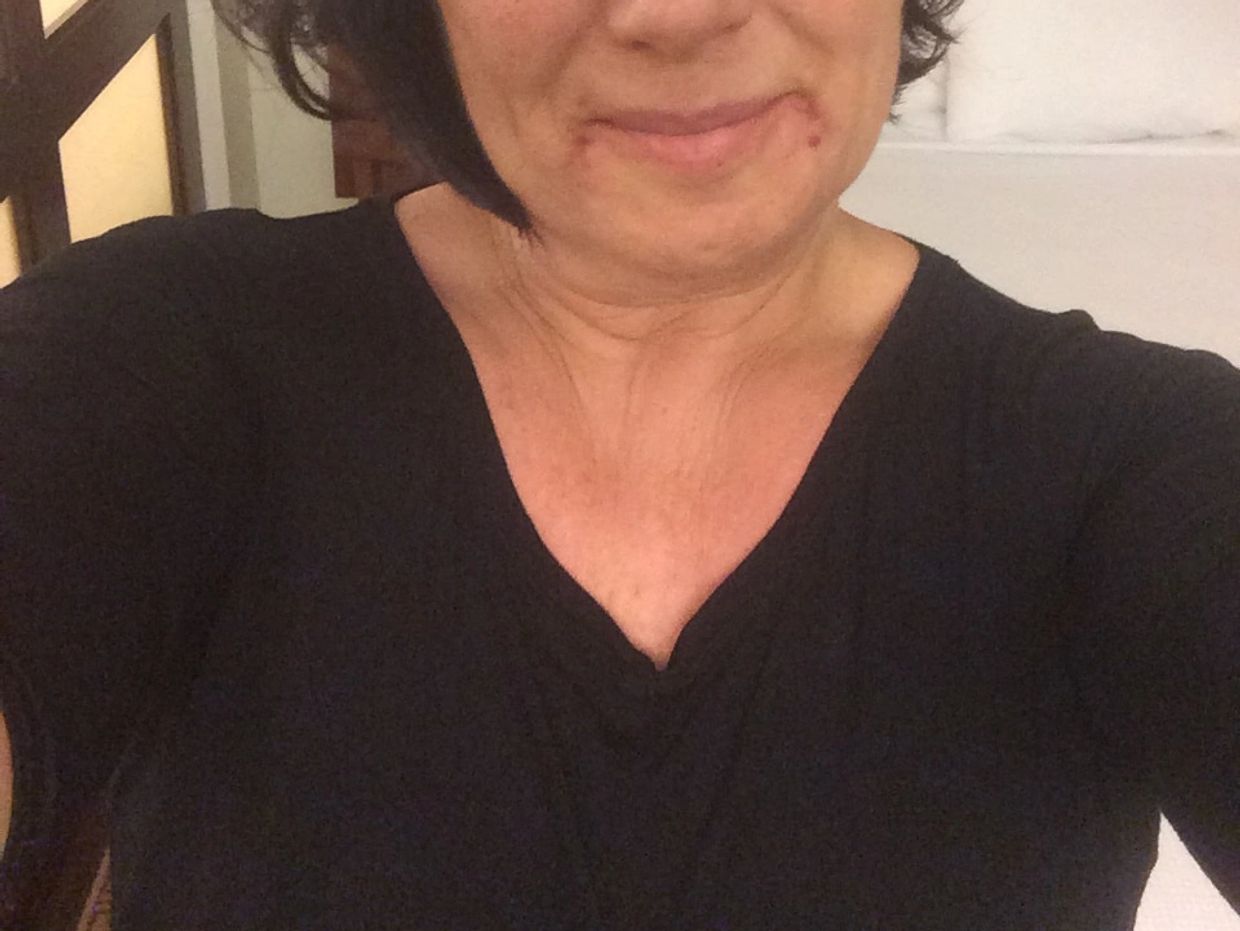 Woman with short hair wearing a black shirt, smiling faintly.