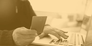 Person holding a credit card and typing on a laptop.