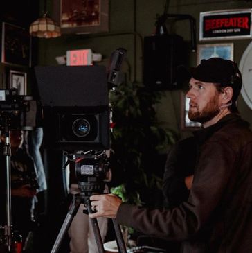 A man operating a professional film camera on set.