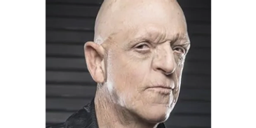 Close-up portrait of an older man with a serious expression and bald head.