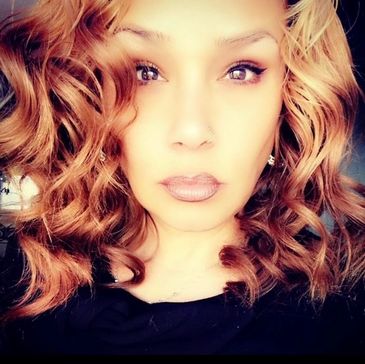 Close-up portrait of a woman with curly hair and neutral expression.