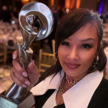 Woman proudly holding a unique trophy at an event.