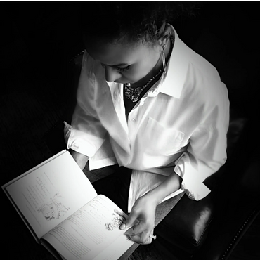 Woman in a white shirt reading a book, captured in black and white.