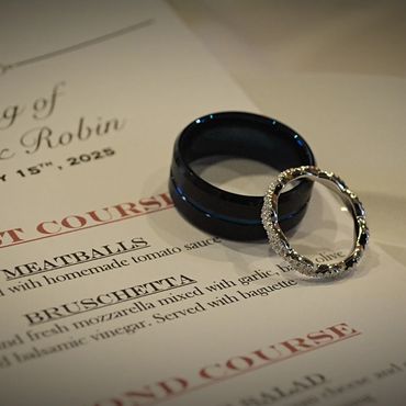 Wedding rings placed on a wedding menu for Harry and Robin's February 2025 celebration.