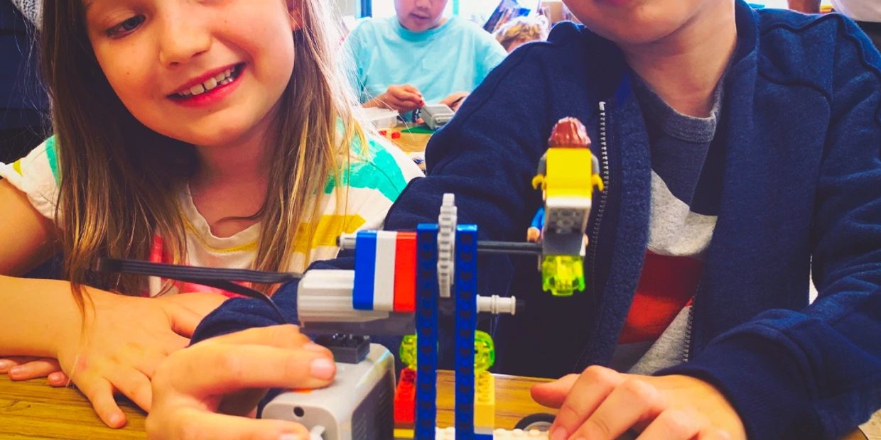 Two kids engaged with a LEGO robotics project.