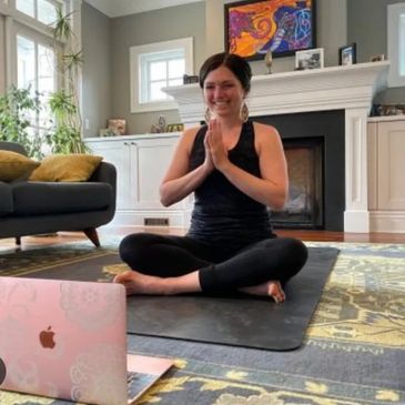 Grateful pranayama student smiles at her computer and gives thanks to her instructor.