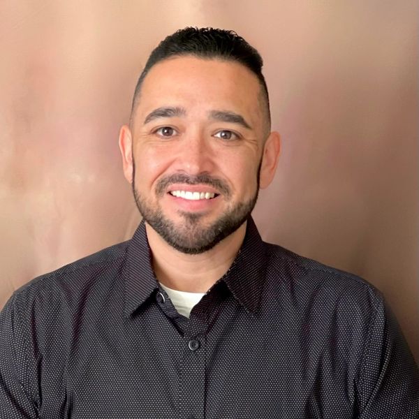 Smiling man with short hair and a neatly trimmed beard wearing a dark shirt.