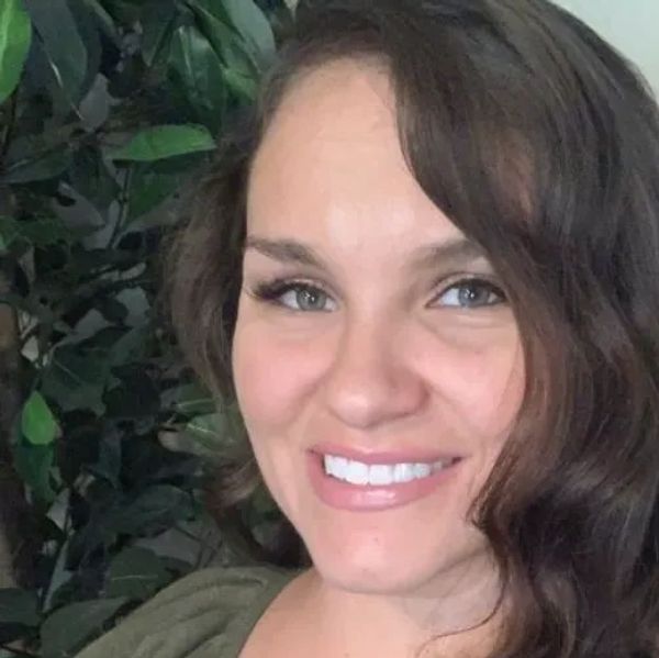 Smiling woman with long brown hair and green top.