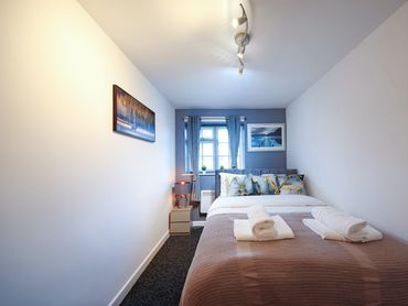 Cozy bedroom with a neatly made bed, blue accents, and soft lighting.
