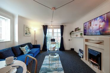 Cozy living room with blue sofa, fireplace, and TV showing Netflix series.