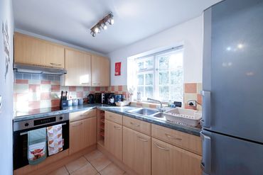 Bright kitchen with wooden cabinets, tiled backsplash, and modern appliances.