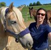 Gillian Poses with Fred, a haflinger horse with another horse in the background.