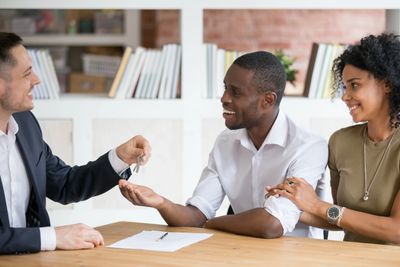 man handing a couple the keys to their new home