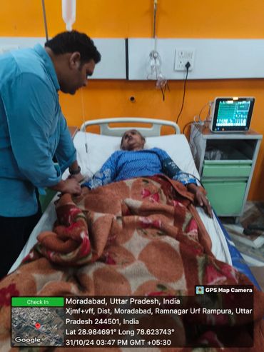 Man caring for a patient in a hospital bed with medical equipment.