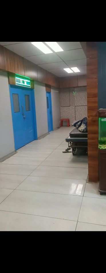 Hospital corridor with blue doors and a waiting area.