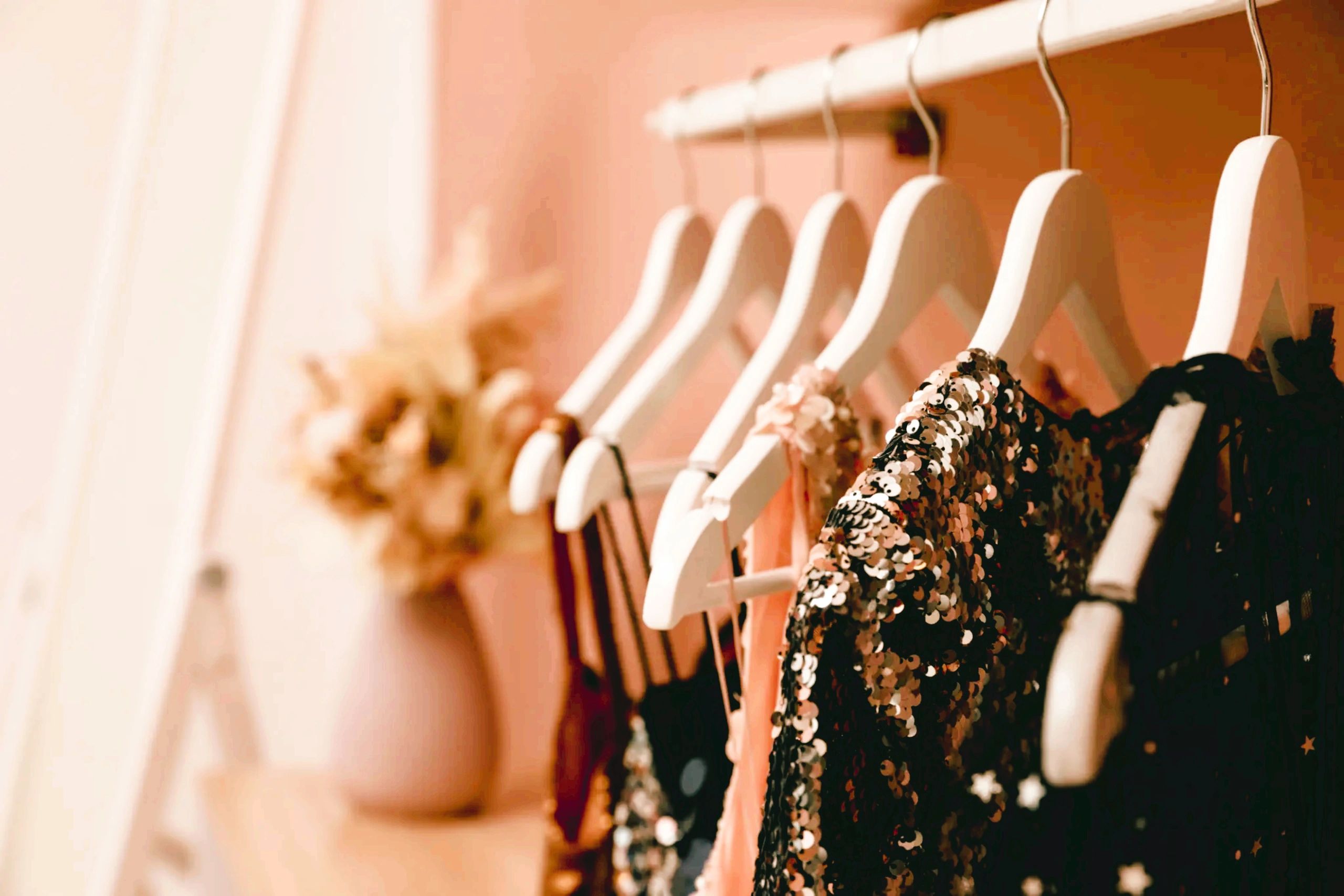 Elegant dresses hanging on white hangers in a softly lit room.