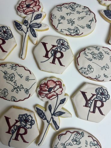 Custom royal icing cookies with 'YR' monogram and hand-painted botanical florals including poppies a