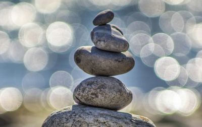 Stack of smooth stones balanced with a sparkling water background.